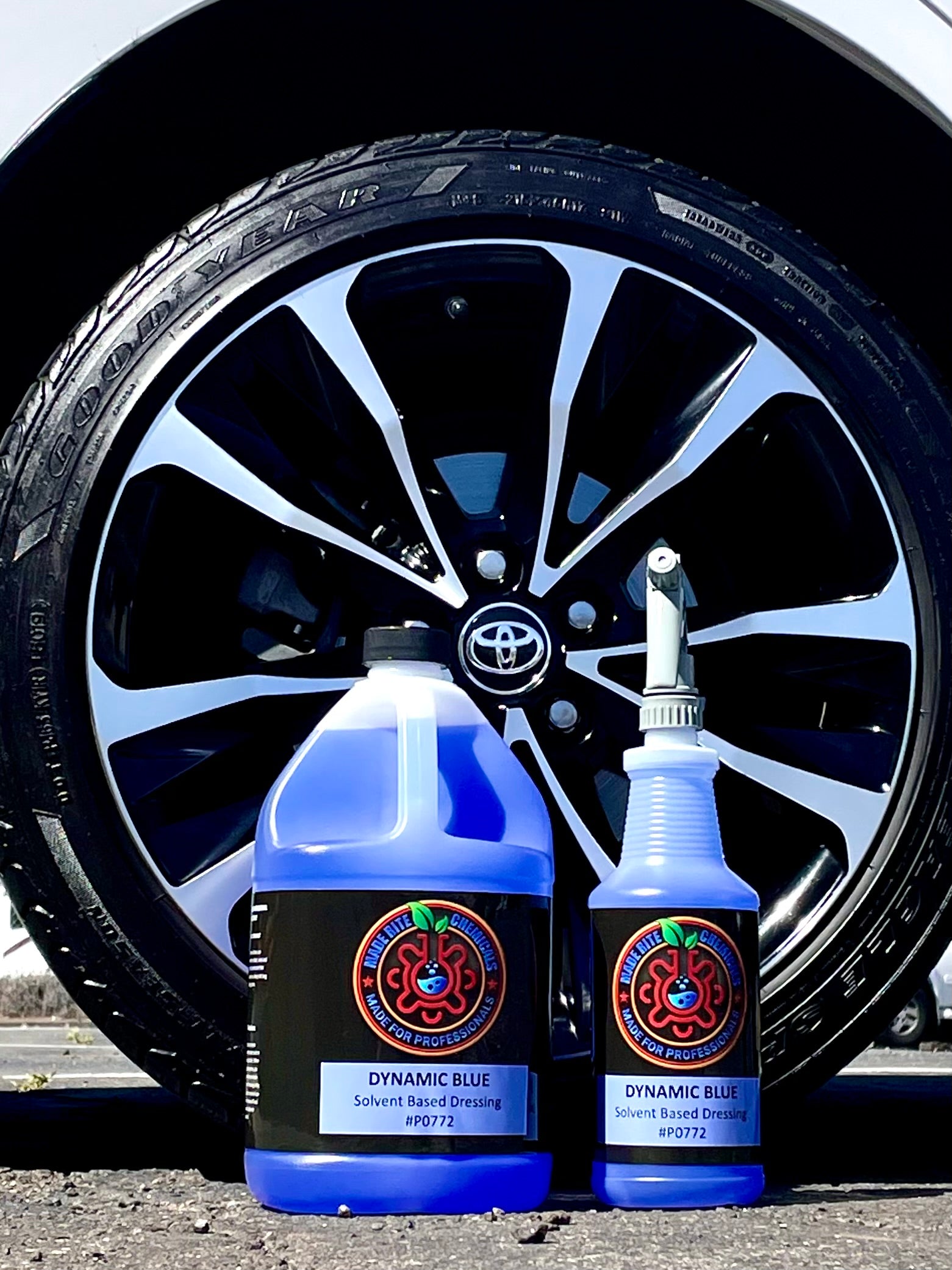 Two bottles of Dynamic Blue car care product in front of a Toyota car tire.